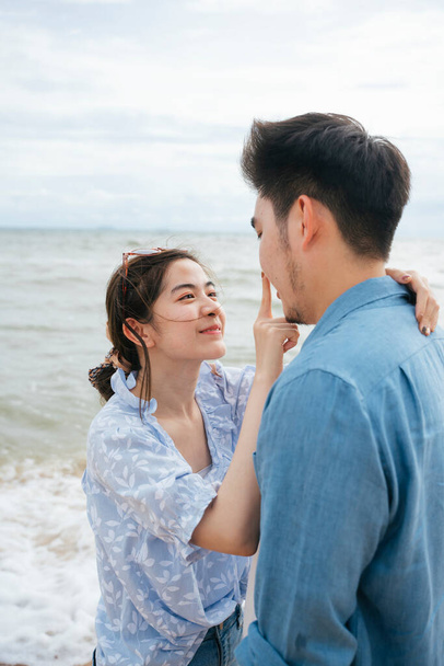 ロマンチックなアジアのカップル旅行者はビーチでお互いの目を見て. - 写真・画像