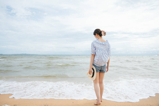 Back view - Young asian traveler woman walking on the beach alone. - Valokuva, kuva