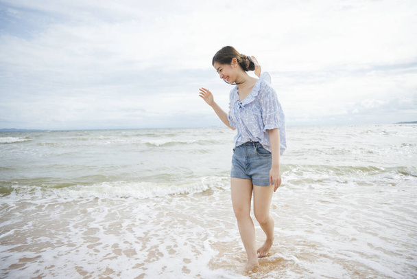 Cheerful young asian traveler woman walking on the beach. - Foto, afbeelding