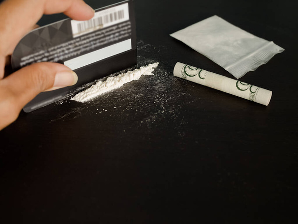 kokaina podzielona rozmazanym wizerunkiem rolki banknotów, karty kredytowej, kokainy w plastikowym opakowaniu. nadużywanie substancji lub pojęcie narkotykowe. - Zdjęcie, obraz