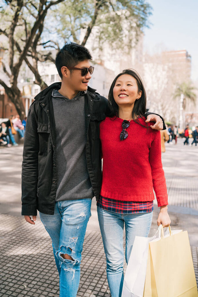 Portrait of young Asian couple in love walking in the city after shopping. Shop concept. - Foto, imagen