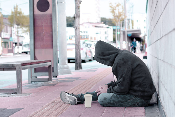 Armer Obdachloser oder Flüchtling schläft auf der Holzbank am Bürgersteig in der Stadt - Foto, Bild