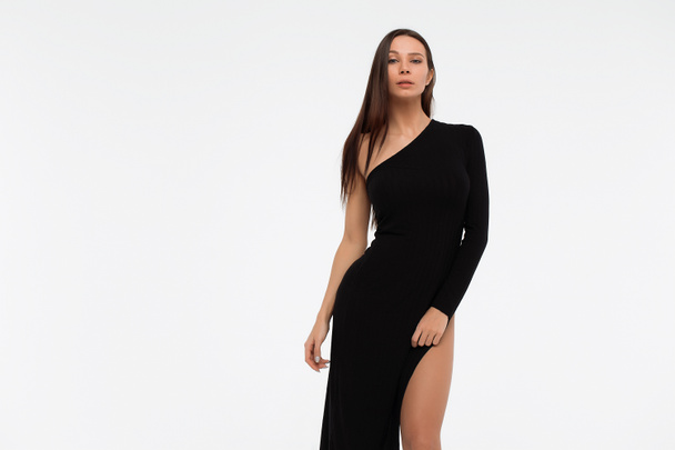 Side view of sensual lady in sexy black dress looking at camera against white background - Foto, Imagem