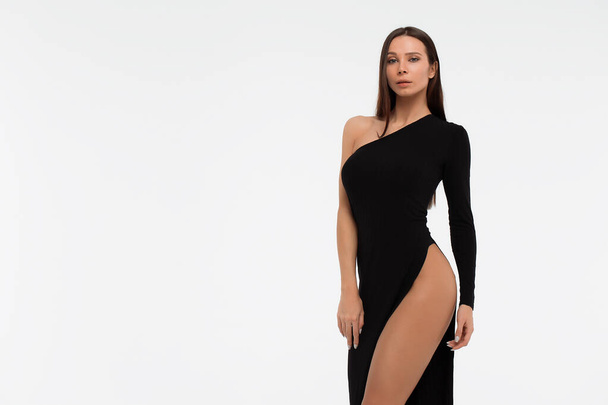 サイドビューの官能的な女性でセクシー黒ドレス見ますカメラに対して白の背景 - 写真・画像
