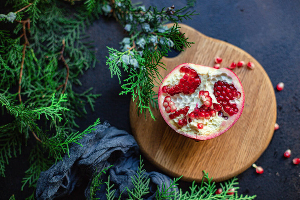 ρόδι κόκκινο φρούτο γλυκό στο τραπέζι και ένα κλαδί του πράσινου χριστουγεννιάτικο δέντρο το νέο έτος νόστιμο θεραπεία εξυπηρετούν μέγεθος top view αντίγραφο χώρο για το κείμενο τροφίμων φόντο ρουστίκ τροφίμων ρουστίκ φόντο - Φωτογραφία, εικόνα