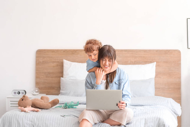 Working mother with little son in bedroom at home - Foto, Imagen