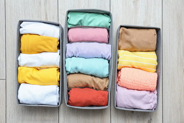 Organizers with clean clothes on wooden floor - Photo, Image
