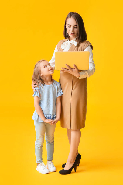 Berufstätige Mutter mit kleiner Tochter auf farbigem Hintergrund - Foto, Bild
