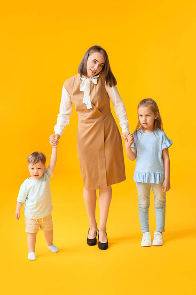 Berufstätige Mutter mit kleinen Kindern auf farbigem Hintergrund - Foto, Bild