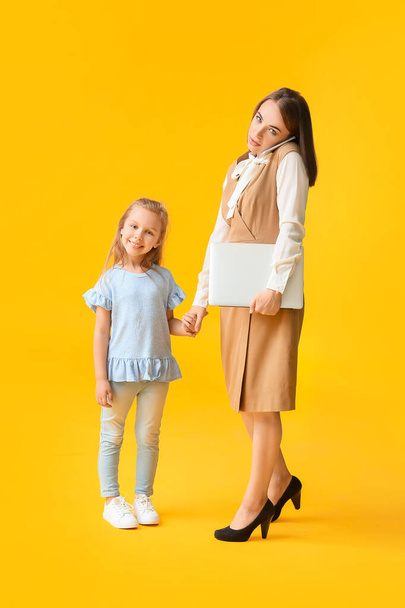 Работающая мать с маленькой дочерью на цветном фоне - Фото, изображение