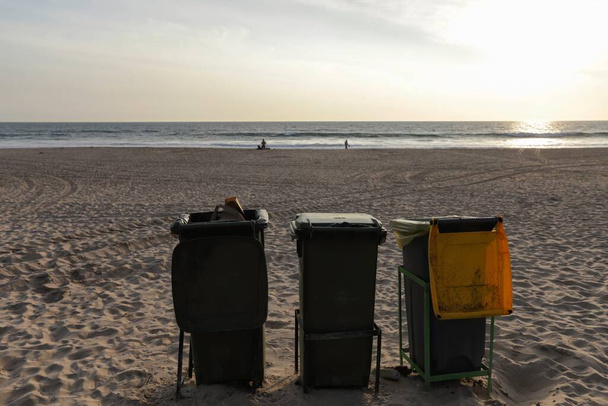 Geïsoleerde vuilnisbakken aan het strand met uitzicht op de Atlantische Oceaan in Costa da Caparica in Lissabon. Milieuconcept levensstijl van afvalbeheer en recyclingbeleid. Portugal, 2020 - Foto, afbeelding