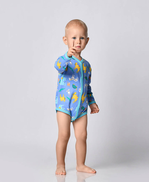 Barefooted baby boy toddler in blue one-piece bodysuit romper with long sleeves stands showing number one forefinger - Foto, Imagen