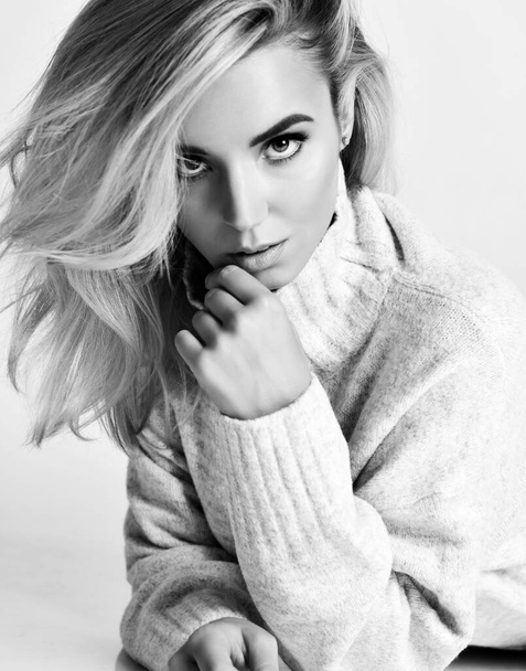 Black and white portrait of young sexy flirting blonde woman vamp in warm knitted sweater looking at camera - Zdjęcie, obraz