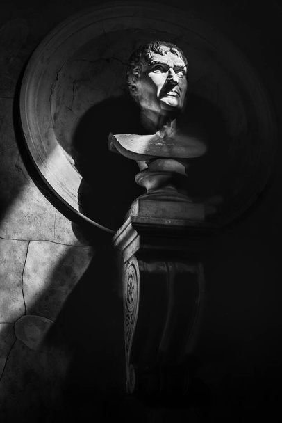 estatua de media longitud retrato fondo vertical blanco y negro en la oscuridad con los rayos del sol filtran a través de las sombras. - Foto, Imagen