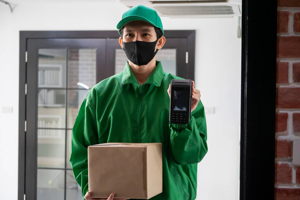 Deliveryman standing and holding smartphone and parcel box - Fotoğraf, Görsel