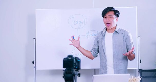 アジアの若い男は、ソーシャルメディア上で共有するためのカメラによって何かをライブ放送コーチング. - 写真・画像