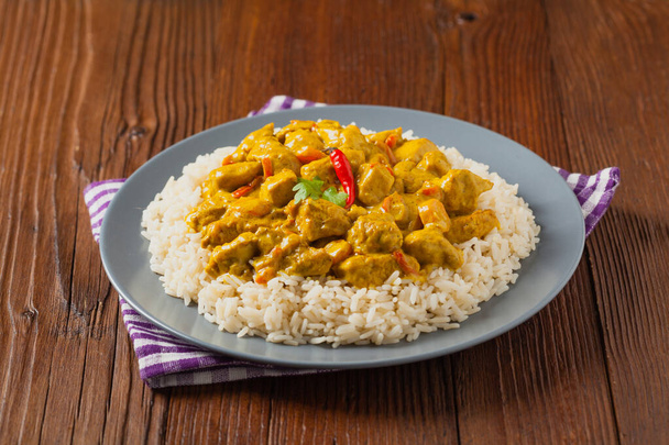 Chicken Curry Sauce. Served with rice. Front view. Natural wooden background. - Foto, Imagen