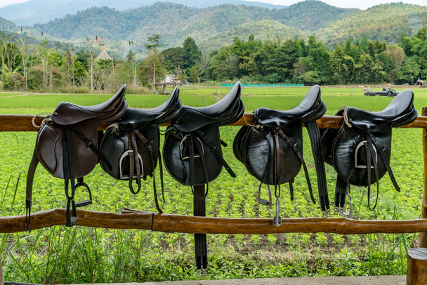седло на деревянном заборе на лошадиной ферме - Фото, изображение