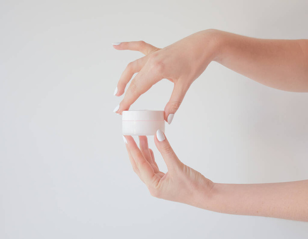 Plastic jar of cream in a female hand isolated on white. Professional cosmetics to restore skin youth, anti-aging cream. Skin care concept. Jar mockup. - Valokuva, kuva