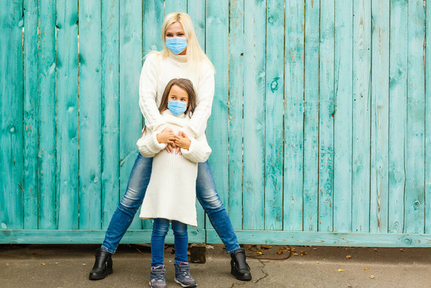 madre e figlia in una maschera medica, essendo in cortile in autunno, da vicino - Foto, immagini