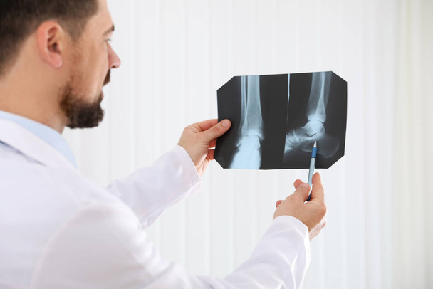 Professional orthopedist examining X-ray picture in his office, focus on hands - Photo, Image