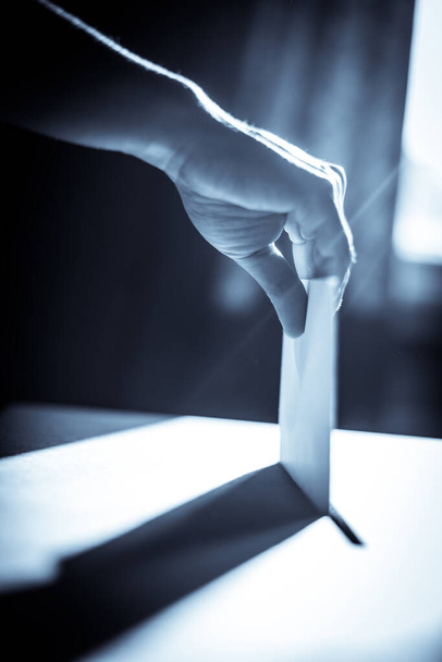 Conceptual image of a person voting, casting a ballot at a polling station, during elections. - Foto, Bild