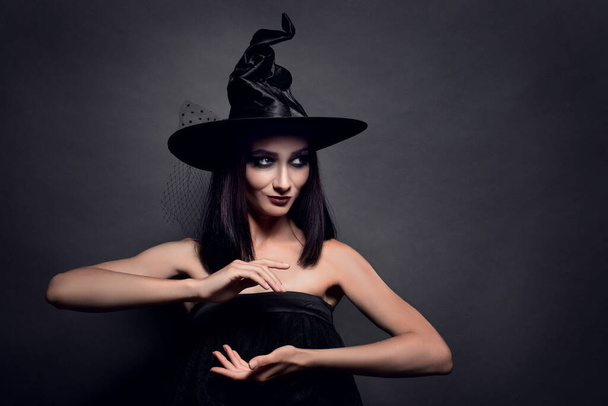 Mysterious witch wearing hat on black background - Photo, Image