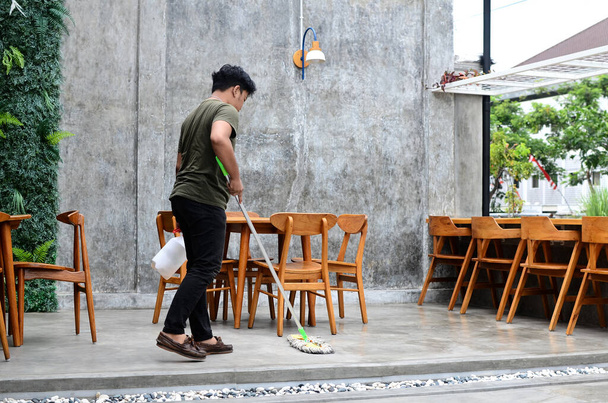 jongeman dweilen de coffeeshop vloer - Foto, afbeelding