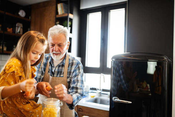Grandfather and his cute grandchild spending happy fun time in kitchen - Фото, зображення