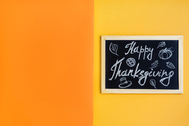 Blackboard with written text "Happy Thanksgiving" on yellow and orange color, top view, space for text. Thanksgiving day background - Photo, Image