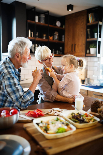 Happy grandparents with beautiful grandchildren making breakfast in kitchen - Foto, Bild