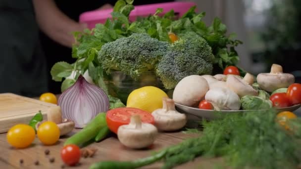 Verduras frescas y frascos de especias en la mesa de la cocina. Cebolla roja picada en el frente. Movimiento lento - Imágenes, Vídeo