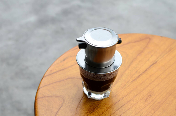 Caffè al latte caldo gocciolante in stile vietnamita. Caffè di latte caldo su un tavolo di legno - Foto, immagini