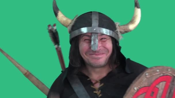 Viking fou dans un casque avec des cornes, avec un bouclier et une grande hache avec des danses et des sourires heureux regard. Portrait d'homme - fond vert - Séquence, vidéo
