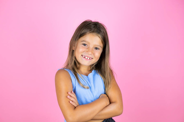 Young beautiful child girl over isolated pink background crossed arms looking at the camera smiling - Valokuva, kuva