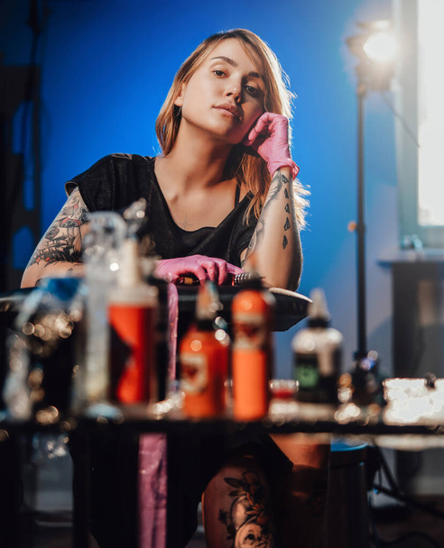 Привлекательный татуировщик с серьезным лицом позирует в своей студии - Фото, изображение