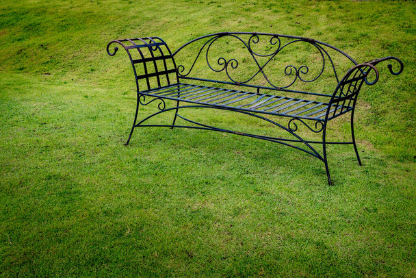 Скамейка металлического парка на зеленой траве в парке - Фото, изображение