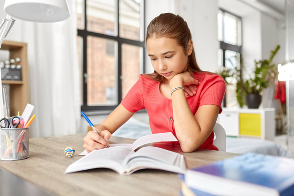 student girl with book writing to notebook at home - Valokuva, kuva