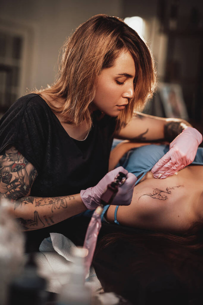 A lány eljött a tetoválásmesterhez, hogy hullámokat rajzoljon a vállára. - Fotó, kép