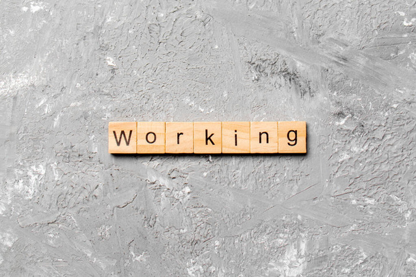Słowo pracy napisane na drewnianym bloku. Tekst roboczy na stole cementowym do projektowania, koncepcja. - Zdjęcie, obraz