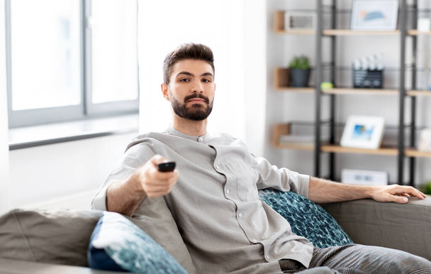 férfi távirányítóval tv-t néz otthon - Fotó, kép