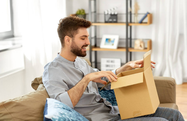 счастливый человек открывает коробку для посылок дома - Фото, изображение