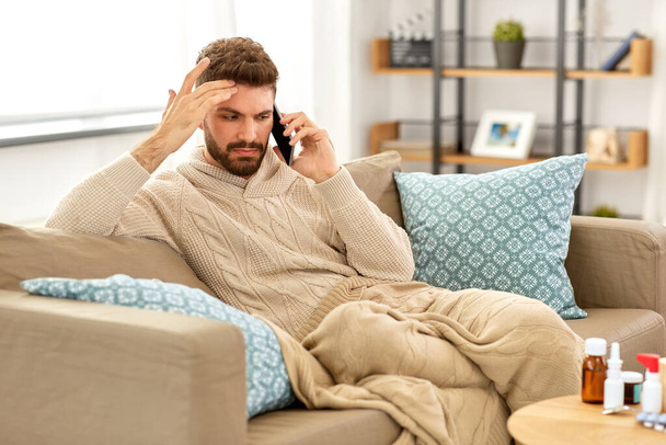 sick young man calling on smartphone at home - Фото, изображение
