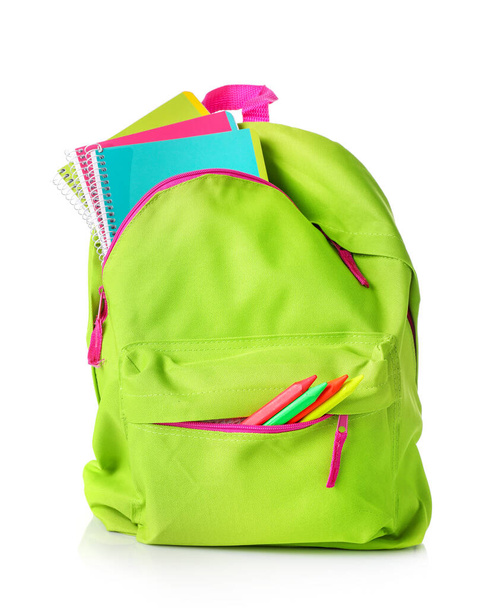 Zielona torba pełna materiałów szkolnych odizolowanych na białym tle. - Zdjęcie, obraz