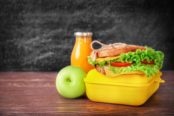 Healthy school lunch box on wooden desk over black chalkboard background. Copy space. - Photo, Image