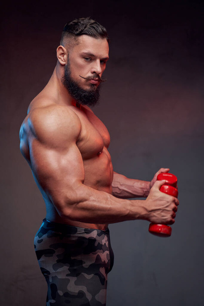 Muscular soldier posing with dumbells in studio background - Zdjęcie, obraz