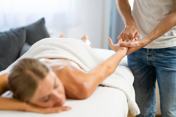Professionele masseur doet therapeutische massage. Vrouw geniet van massage in haar huis. jonge vrouw het krijgen van ontspannende lichaam massage. - Foto, afbeelding