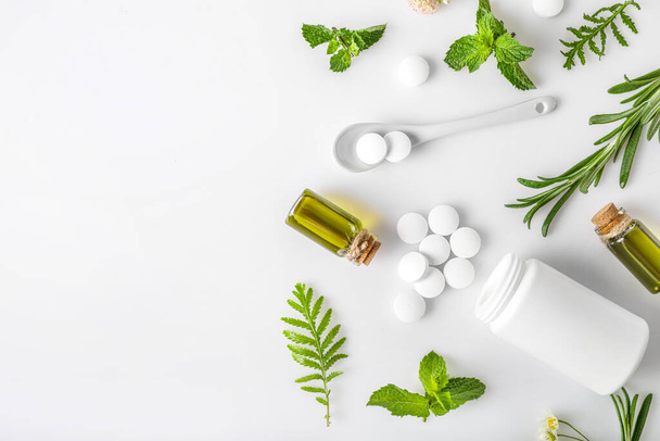Various medicinal herbs with herbal pills and aroma oil isolated on white background. Top view. Copy space. Herbal medicine concept. - Photo, Image
