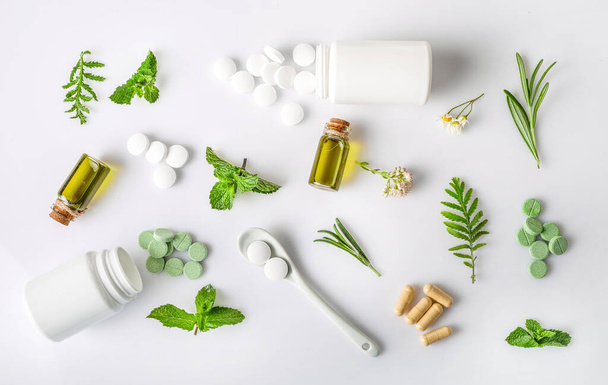 Pose plate de diverses herbes médicinales avec des pilules à base de plantes et de l'huile d'arôme isolée sur fond blanc. Vue de dessus. Concept de phytothérapie. - Photo, image