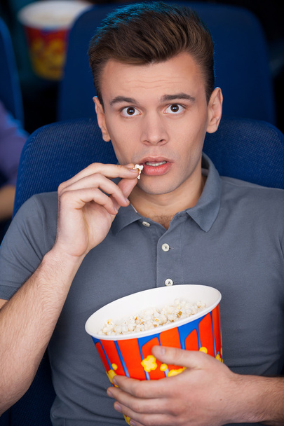 Man eating popcorn at the cinema - Fotó, kép